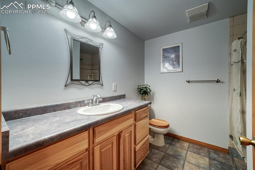 13770 Woodlake Road Elbert, CO 80106 - Photo 17 of 43 a bathroom with a granite countertop sink a toilet and a mirror