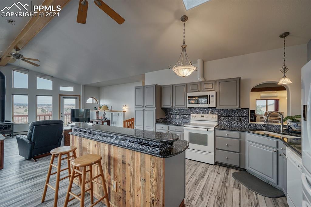 13770 Woodlake Road Elbert, CO 80106 - Photo 8 of 43 a kitchen with stainless steel appliances granite countertop a stove top oven a sink dishwasher a dining table and chairs with wooden floor