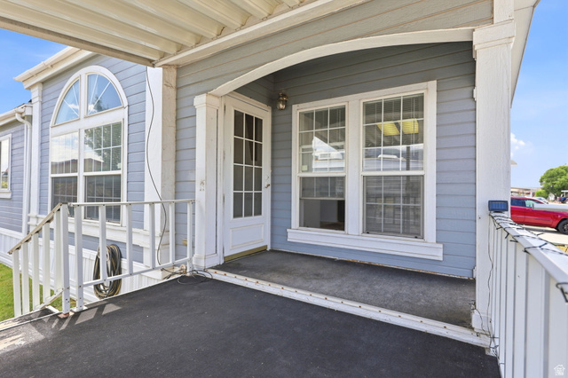 2491 Highway 89, Unit 614 Pleasant View, UT 84404 - Photo 5 of 27 Covered front porch entry with light blue siding, white railings, and a glass-paneled front door