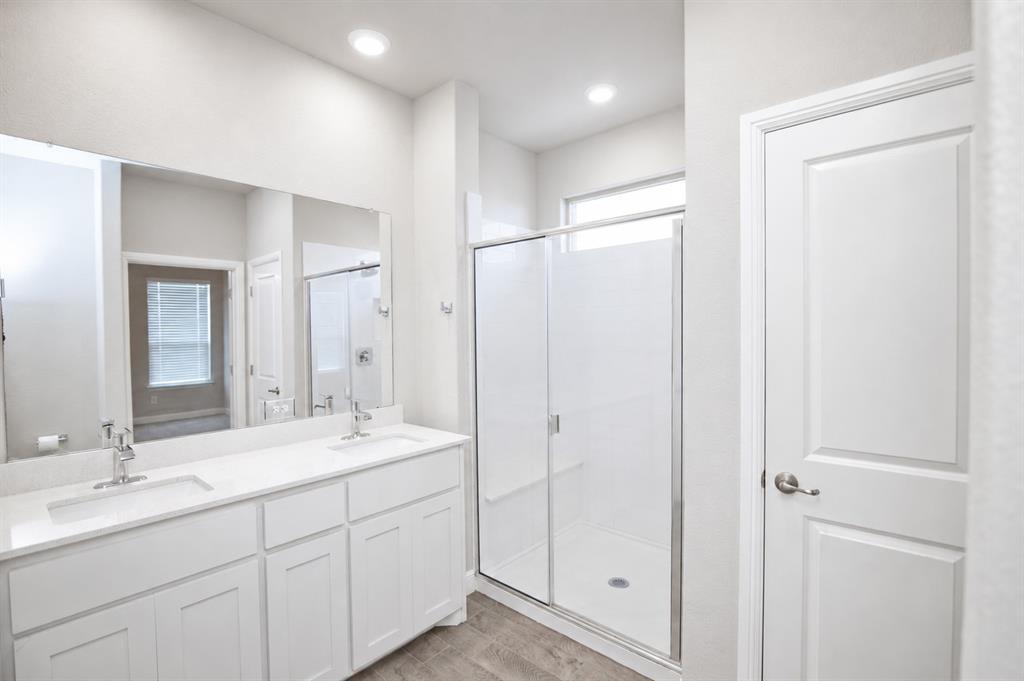 1804 Mensa Drive Haslet, TX 76052 - Photo 13 of 30 Bathroom featuring a double vanity with white cabinetry, a large frameless mirror, and a walk-in shower with a glass enclosure