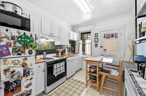a kitchen that has a lot of white cabinets and stainless steel appliances
