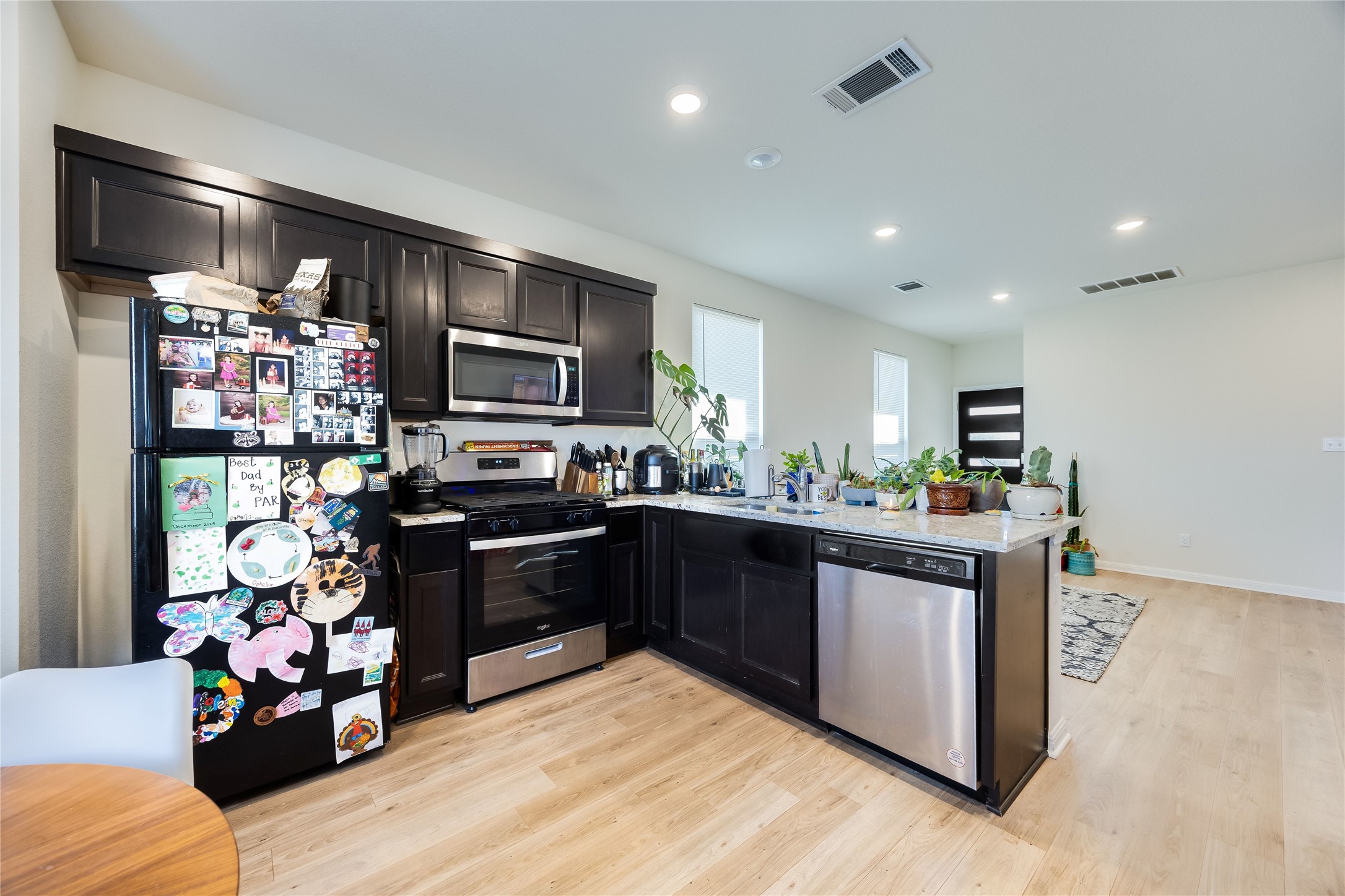 263 Tolo Drive Elgin, TX 78621 - Photo 6 of 12 Kitchen with appliances with stainless steel finishes, a peninsula, light wood-style flooring, recessed lighting, and light stone countertops
