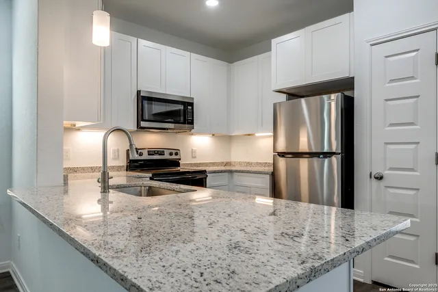 a kitchen with granite countertop a refrigerator a stove and a sink