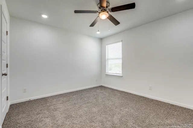 an empty room with a window and a fan