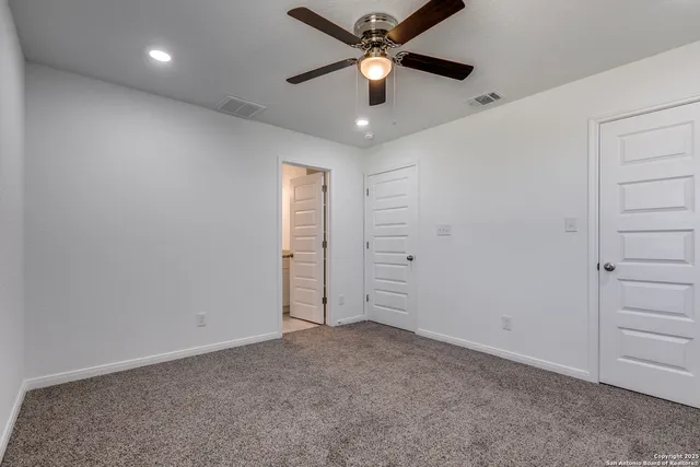 an empty room with closet and a ceiling fan