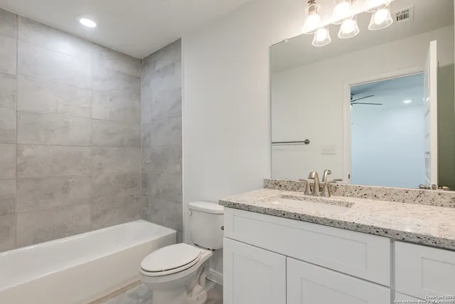 a bathroom with a granite countertop sink a toilet a mirror a bathtub and shower
