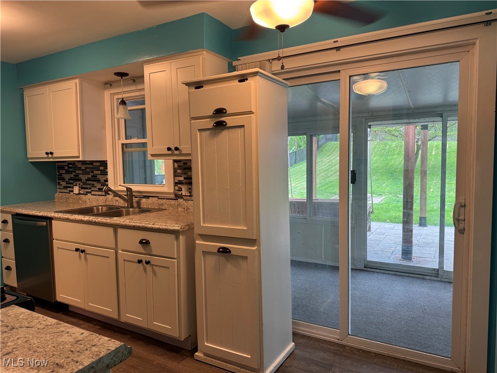 1139 Kessel Avenue Akron, OH 44310 - Photo 6 of 36 Kitchen featuring a sink, dishwashing machine, dark wood finished floors, tasteful backsplash, and white cabinetry