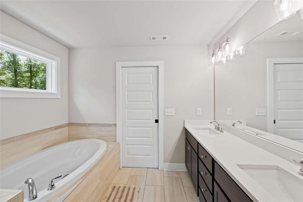 2362 Browns Mill Road Southeast Atlanta, GA 30315 - Photo 26 of 41 a bathroom with a tub a double vanity sink a window and a mirror