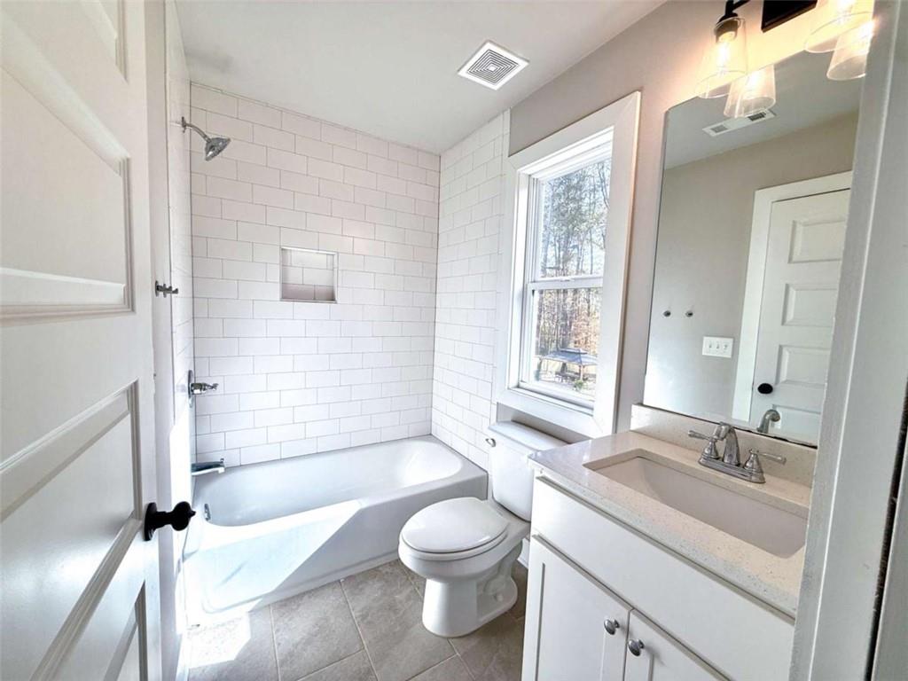 2362 Browns Mill Road Southeast Atlanta, GA 30315 - Photo 30 of 41 a bathroom with a granite countertop sink toilet a large mirror a bathtub and shower