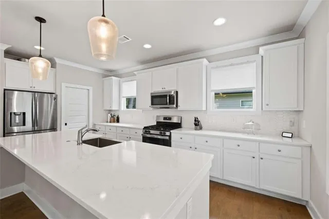 a kitchen with stainless steel appliances a stove a sink a microwave a center island and cabinets