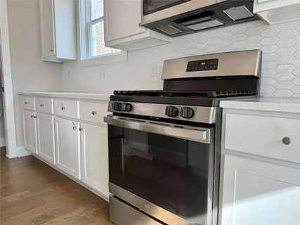 a kitchen with white cabinets and black appliances