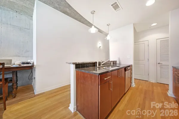 a kitchen with stainless steel appliances granite countertop a sink a stove a refrigerator and a oven with wooden floor