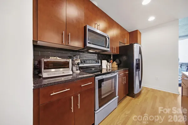 a kitchen with stainless steel appliances granite countertop a refrigerator a stove a sink and a microwave