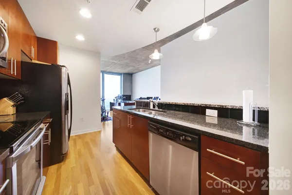 a kitchen with stainless steel appliances granite countertop a sink a stove and a refrigerator