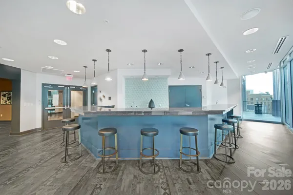 a kitchen with stainless steel appliances granite countertop a stove a sink a oven a dining table and chairs with wooden floor