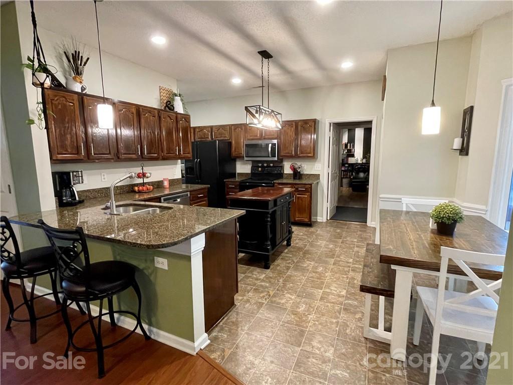 6607 Reedy Creek Road Charlotte, NC 28215 - Photo 11 of 27 a kitchen with kitchen island granite countertop a sink counter and chairs