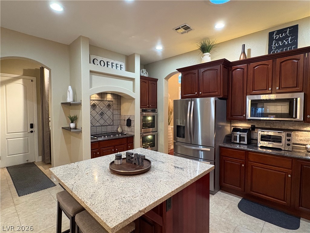 977 Rhyolite Terrace Henderson, NV 89011 - Photo 12 of 33 Rich wood cabinetry and stone countertops anchor this functional kitchen space.