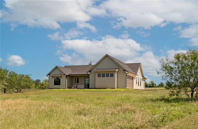 a front view of house with yard and ocean