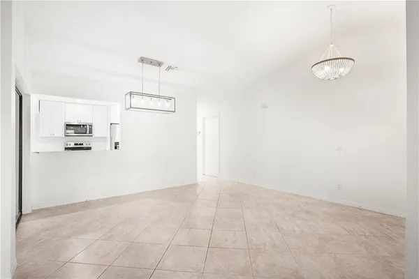 an empty room with kitchen view and refrigerator