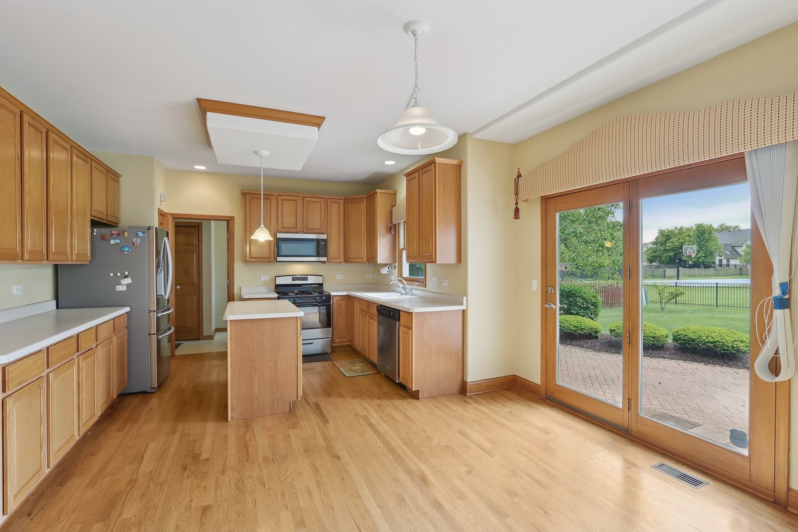 548 Asbury Drive Aurora, IL 60502 - Photo 12 of 48 a kitchen with stainless steel appliances kitchen island granite countertop a refrigerator a stove top oven a sink and dishwasher with wooden floor