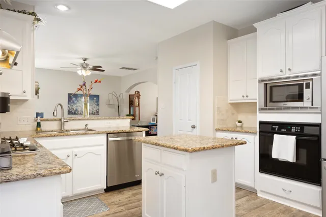 a kitchen with granite countertop a sink stove and cabinets