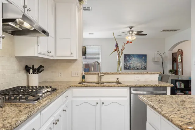 a kitchen with stainless steel appliances granite countertop a sink stove oven and white cabinets