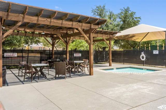a backyard of a house with table and chairs under an umbrella