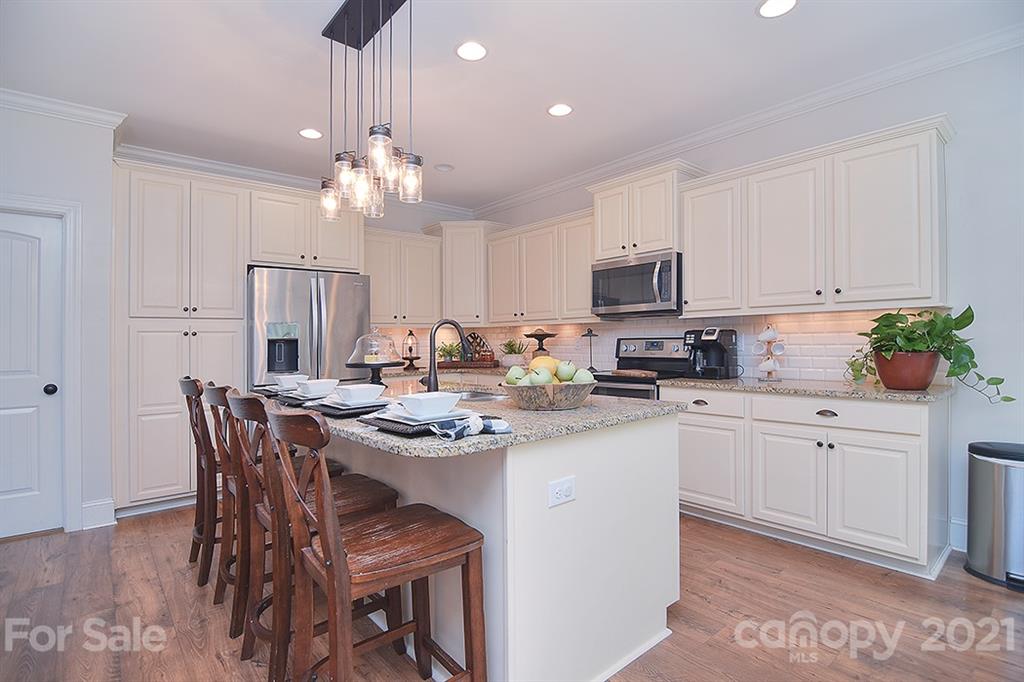 5813 Dudley Road Monroe, NC 28112 - Photo 11 of 44 a kitchen with stainless steel appliances granite countertop a white stove top oven a sink dishwasher a dining table and chairs with wooden floor