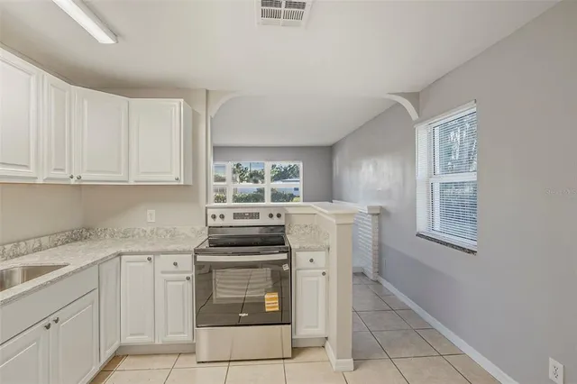 a kitchen with stainless steel appliances granite countertop a sink and dishwasher a refrigerator with white cabinets