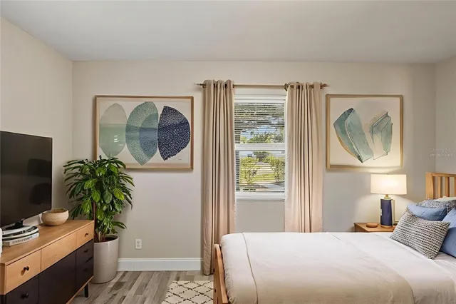a bedroom with a bed and a potted plant on the dresser