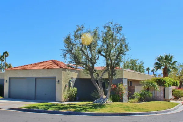 a front view of a house with a yard and potted plants