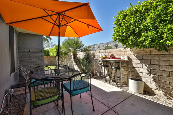 a backyard view of a house with table and chairs under an umbrella