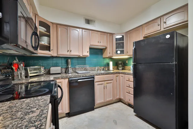 a kitchen with stainless steel appliances granite countertop a refrigerator a stove and a sink
