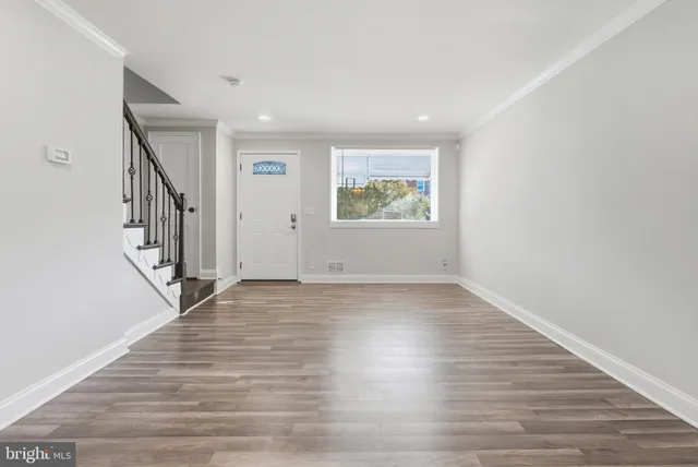a view of an empty room with wooden floor and stairs