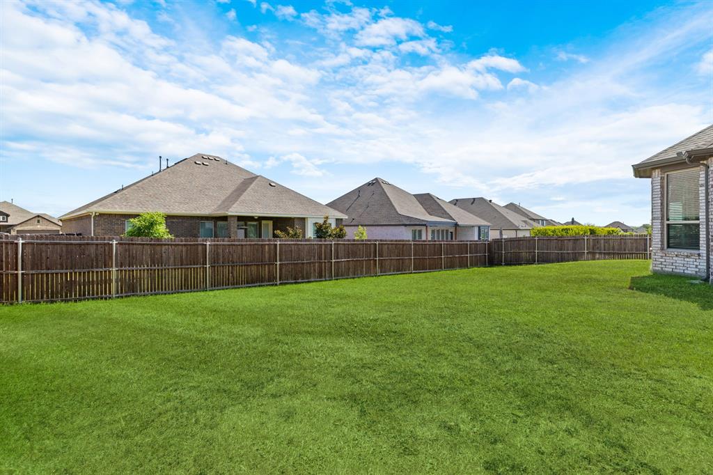 915 Timber Ridge Drive Justin, TX 76247 - Photo 38 of 39 Expansive backyard featuring a large green lawn and a full-height privacy fence