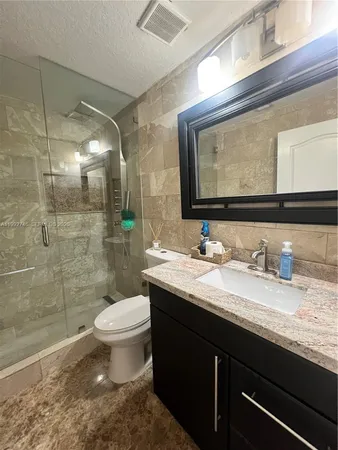 a bathroom with a granite countertop sink a toilet and a mirror