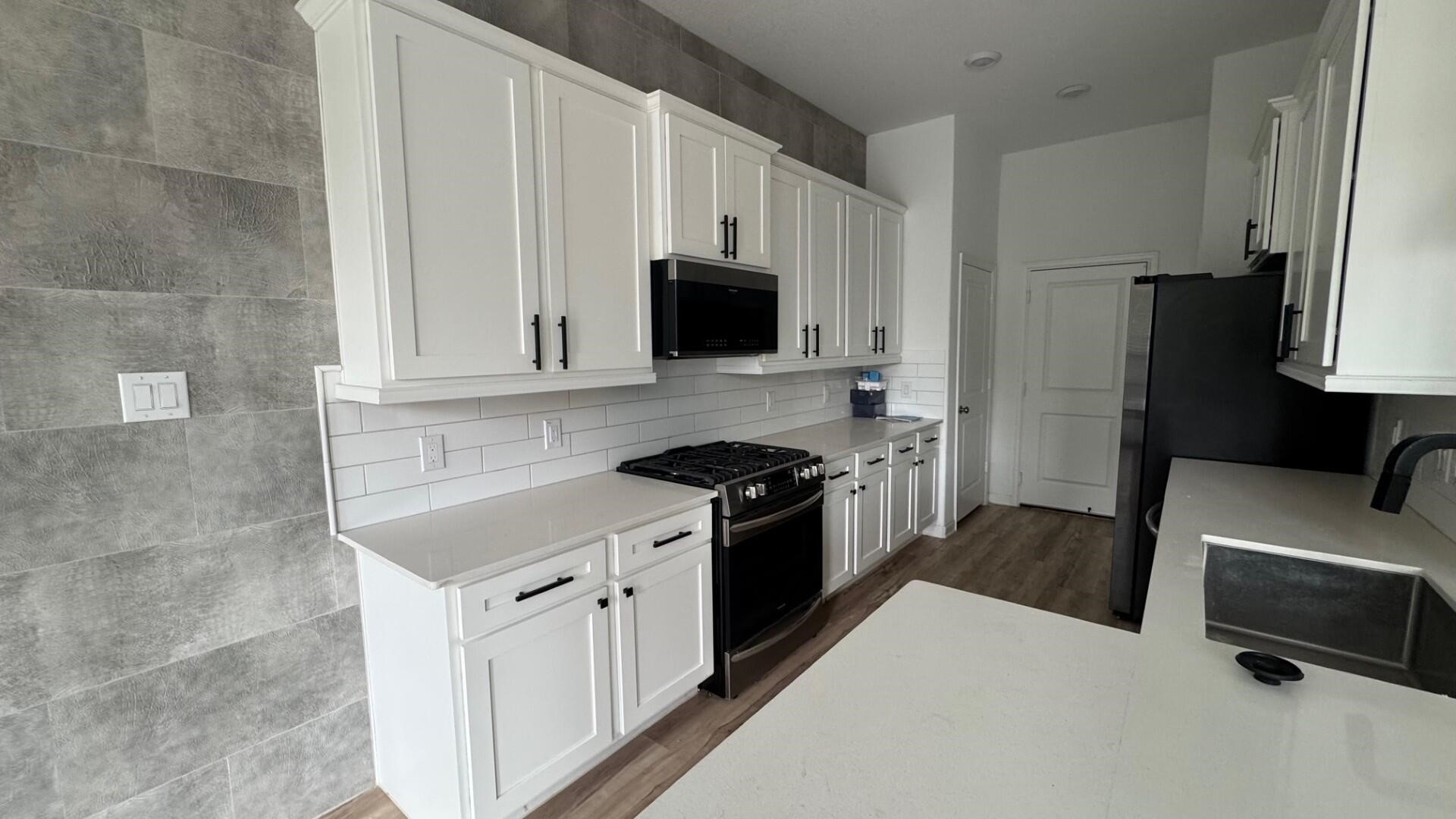 975 Lars Trek Trail Conroe, TX 77304 - Photo 27 of 36 a kitchen with a refrigerator stove and white cabinets