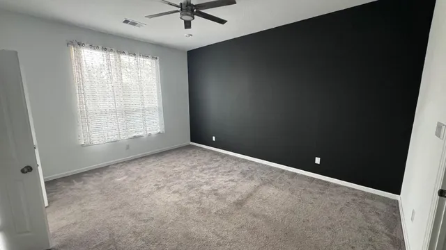 an empty room with windows and fan