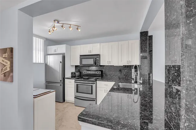 a kitchen with stainless steel appliances granite countertop a stove a refrigerator and a sink