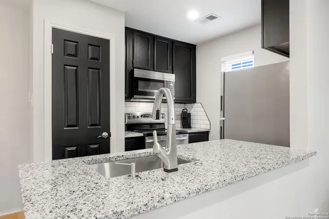 a kitchen with stainless steel appliances kitchen island granite countertop a refrigerator and a stove top oven