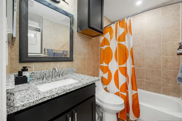 a bathroom with a granite countertop sink and a toilet
