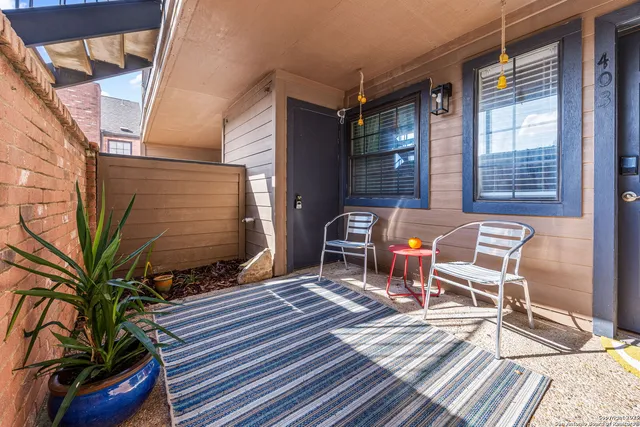 a patio with table and chairs and potted plants