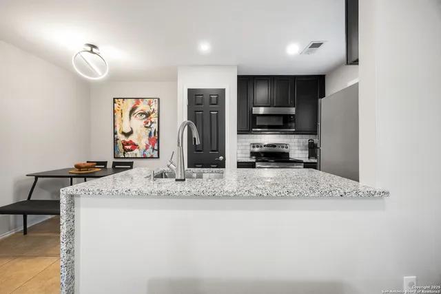 a view of kitchen with stainless steel appliances granite countertop sink stove and refrigerator