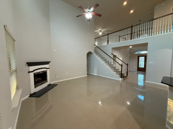 a view of an empty room with wooden floor fireplace and a window