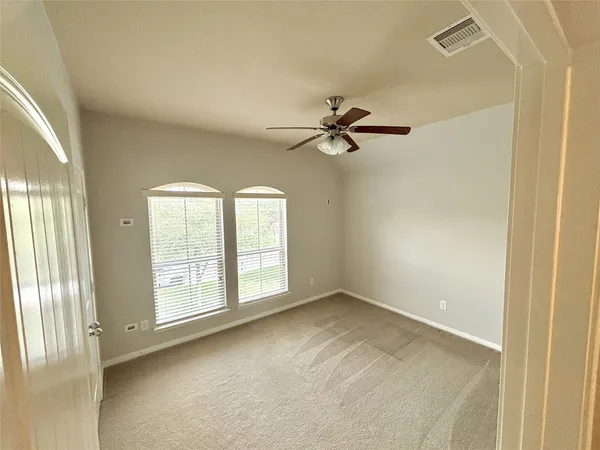 an empty room with windows and fan