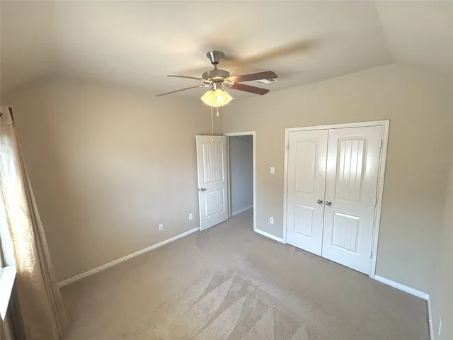 an empty room with chandelier fan and windows