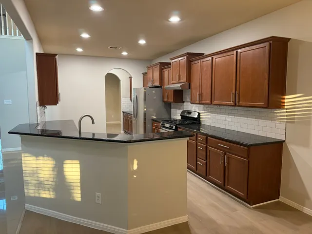 a kitchen with stainless steel appliances granite countertop a sink a stove and cabinets