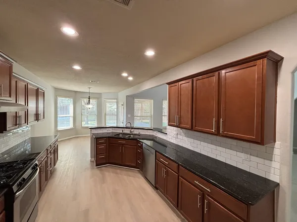a large kitchen with stainless steel appliances granite countertop a sink stove and cabinets