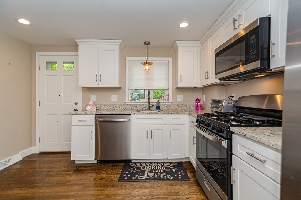 155 Spring Street Stoneham, MA 02180 - Photo 6 of 30 a kitchen with stainless steel appliances granite countertop a stove a sink and a microwave