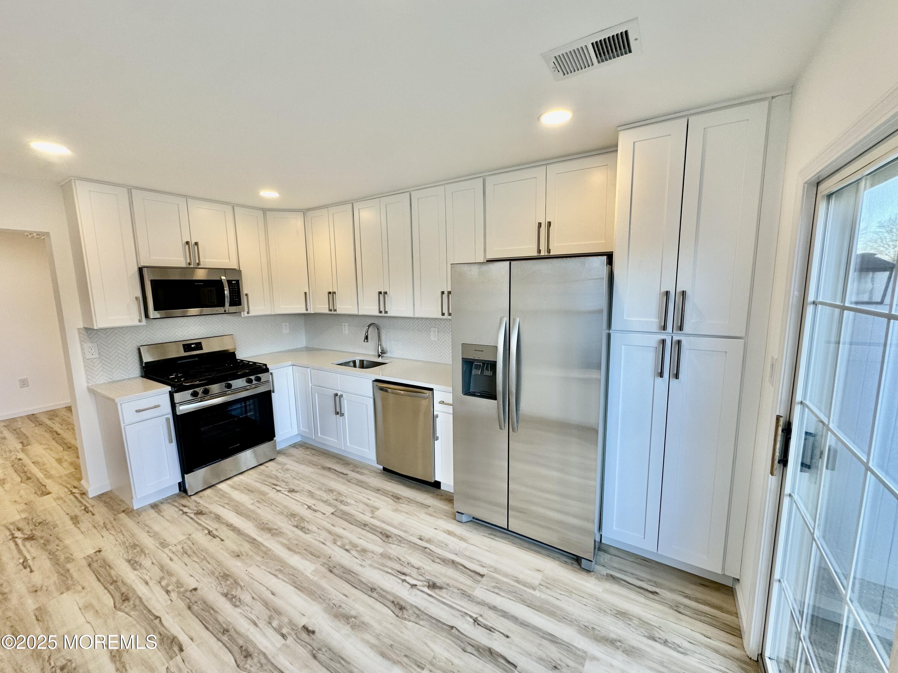 51 Picket Place Freehold, NJ 07728 - Photo 11 of 47 a kitchen with a refrigerator a stove top oven and wooden floor